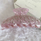 A close-up of a pink marbled claw clip with rhinestones