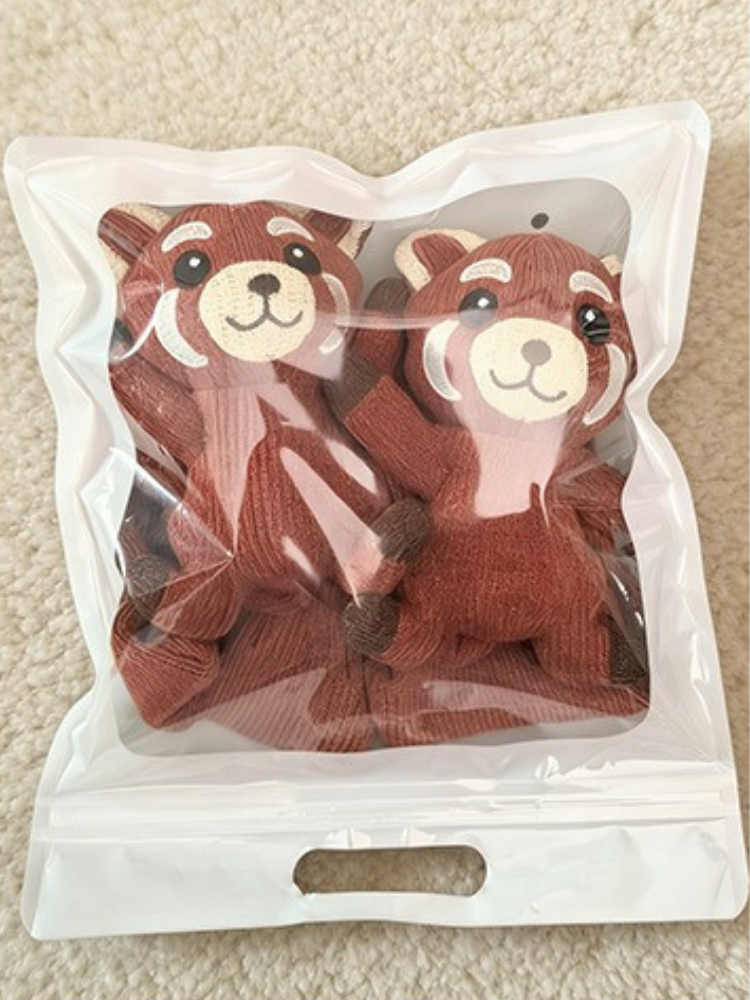 Two red panda character crew socks packaged in a clear bag
