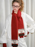 Close-up of a red scarf with a snowman design and fringe detail.