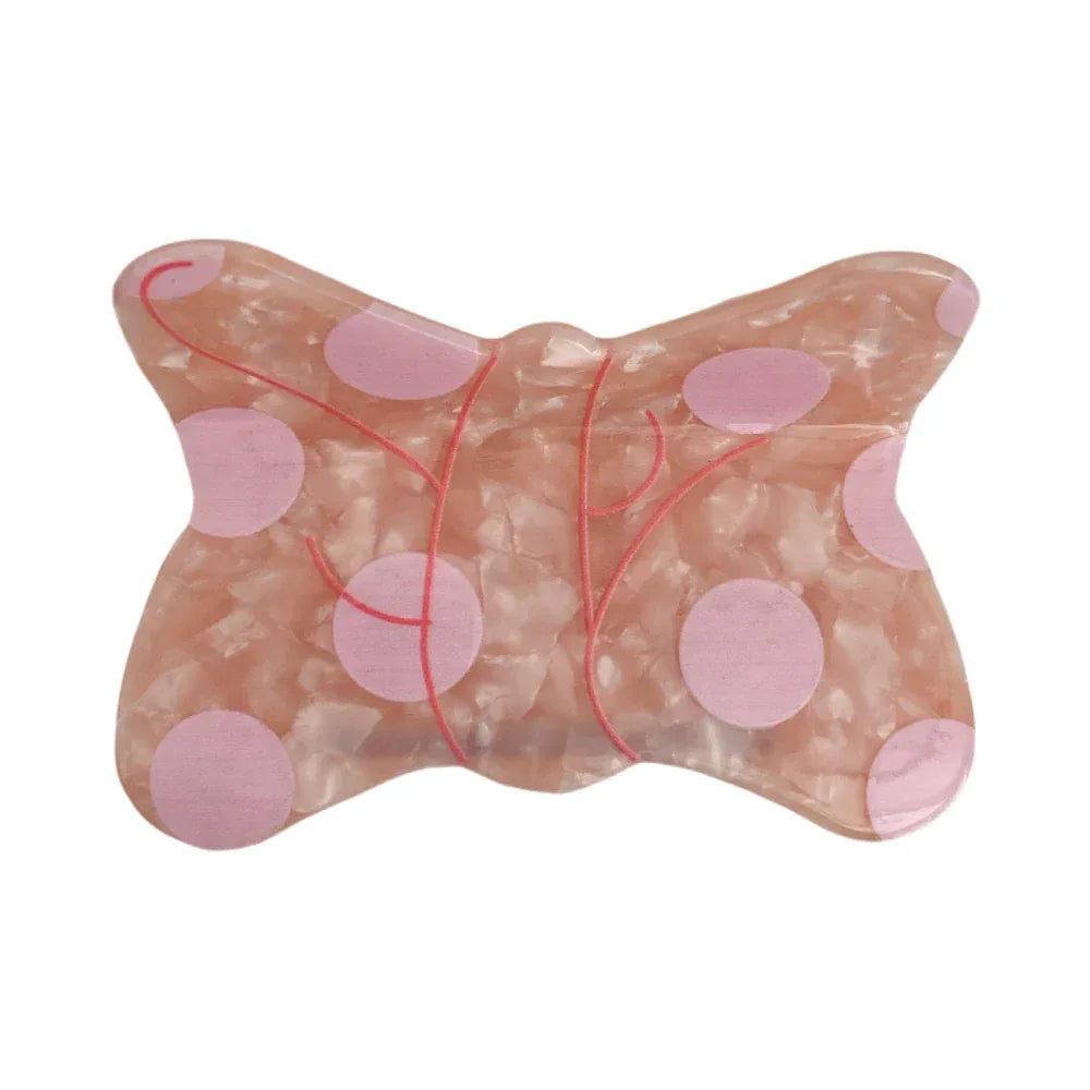 Pink butterfly-shaped hair clip with light pink polka dots and thin red linear accents. Main image