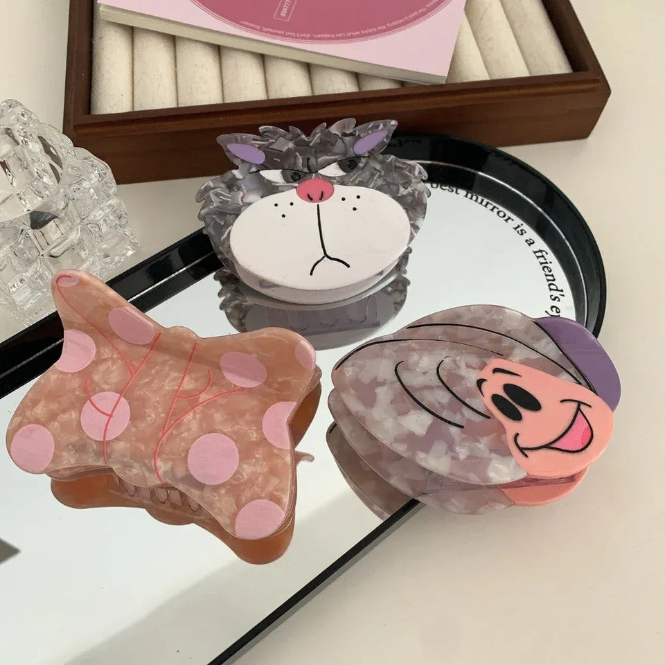 Three decorative hair clips, including a butterfly, a cat face, and a snail, displayed on a mirror. Secondary image