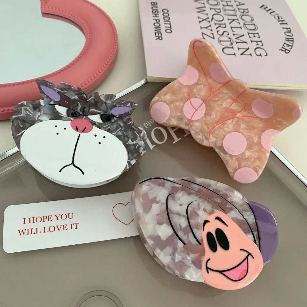 A collection of decorative hair clips, featuring a butterfly, a cat, and a snail, arranged with other accessories.