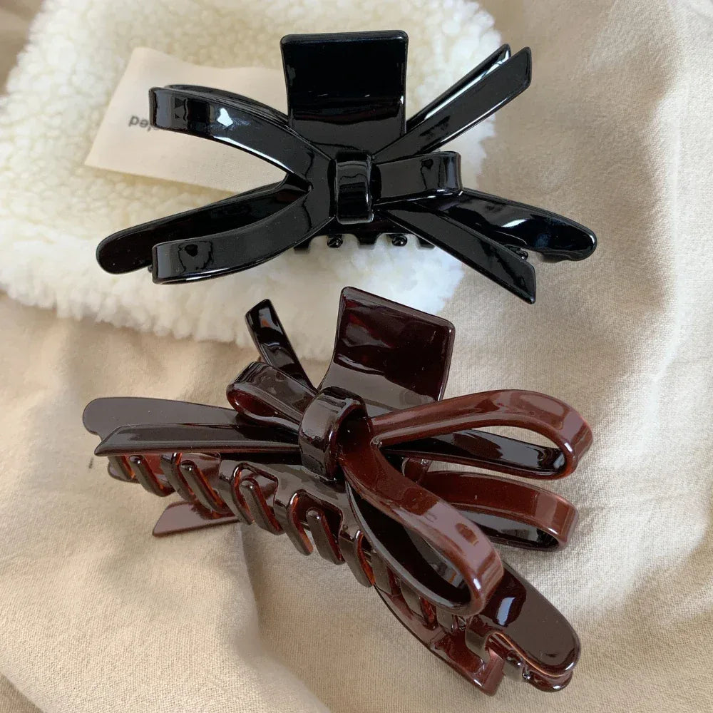 black and brown glossy bow claw clips on a fluffy white surface