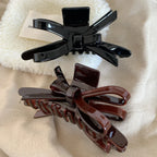 black and brown glossy bow claw clips on a fluffy white surface