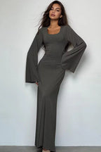 Woman wearing a long-sleeved, ribbed maxi dress with bell sleeves and a square neckline in a charcoal gray color.