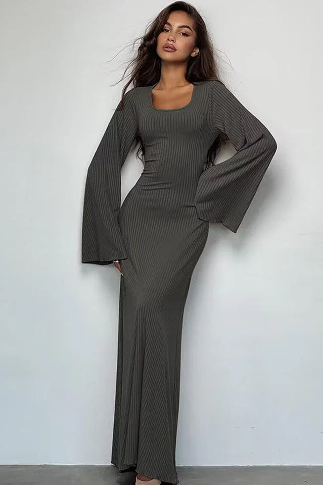 Woman wearing a long-sleeved, ribbed maxi dress with bell sleeves and a square neckline in a charcoal gray color.