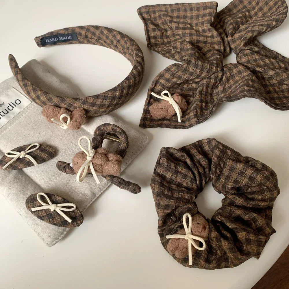 assortment of brown plaid hair accessories, featuring scrunchies, headbands, clips, and barrettes with teddy bear embellishments