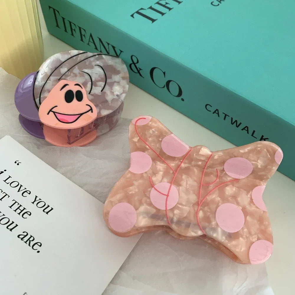 A pink butterfly hair clip with polka dots is placed next to a book and a card with text.