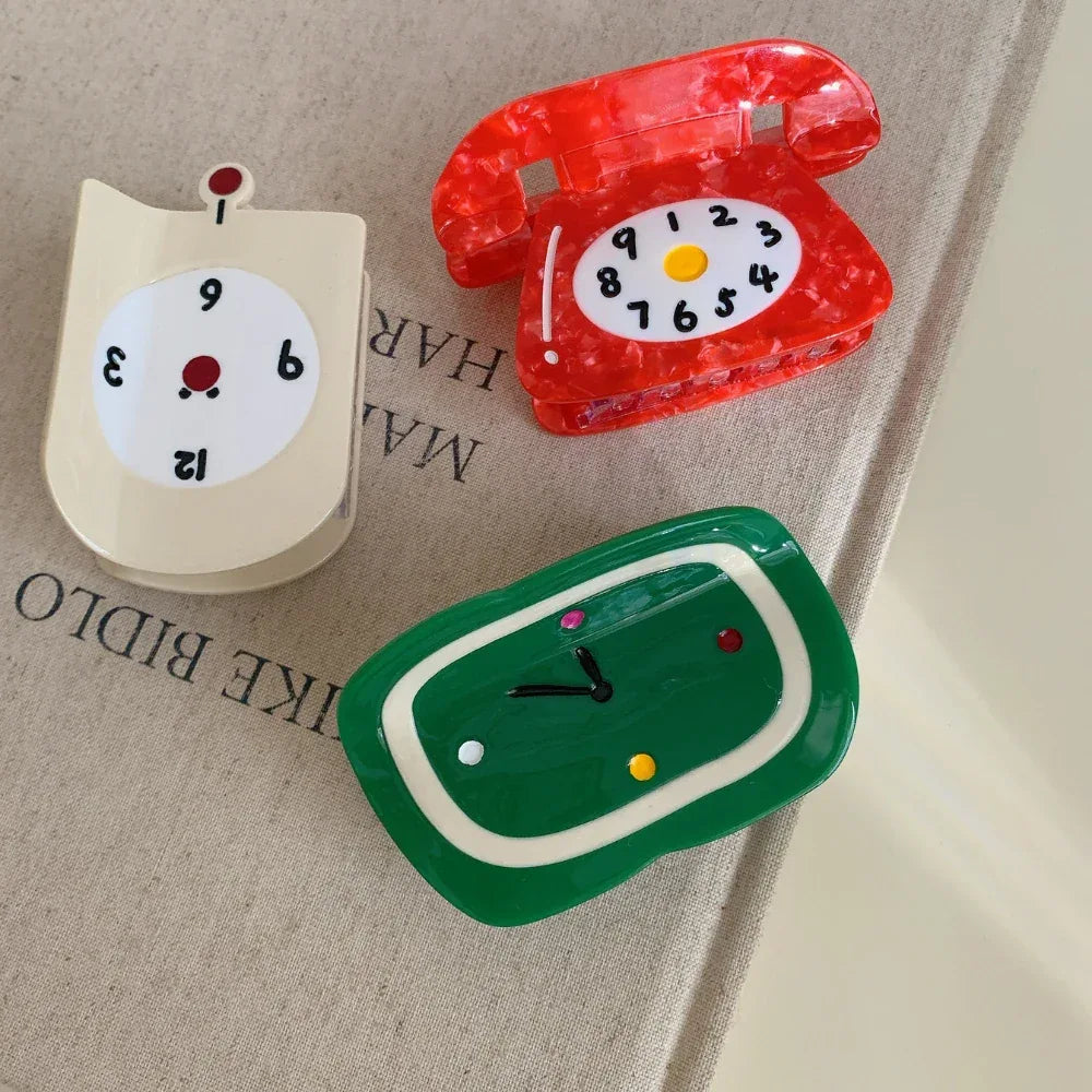 Close-up of novelty hair clips shaped like clocks and a telephone