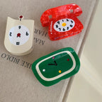 Close-up of novelty hair clips shaped like clocks and a telephone