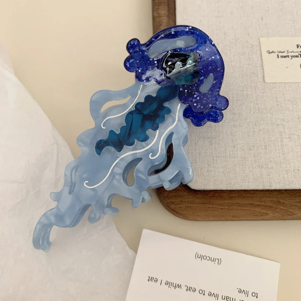 Close-up of a blue glitter jellyfish hair clip with translucent tentacles and white swirls