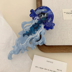 Close-up of a blue glitter jellyfish hair clip with translucent tentacles and white swirls