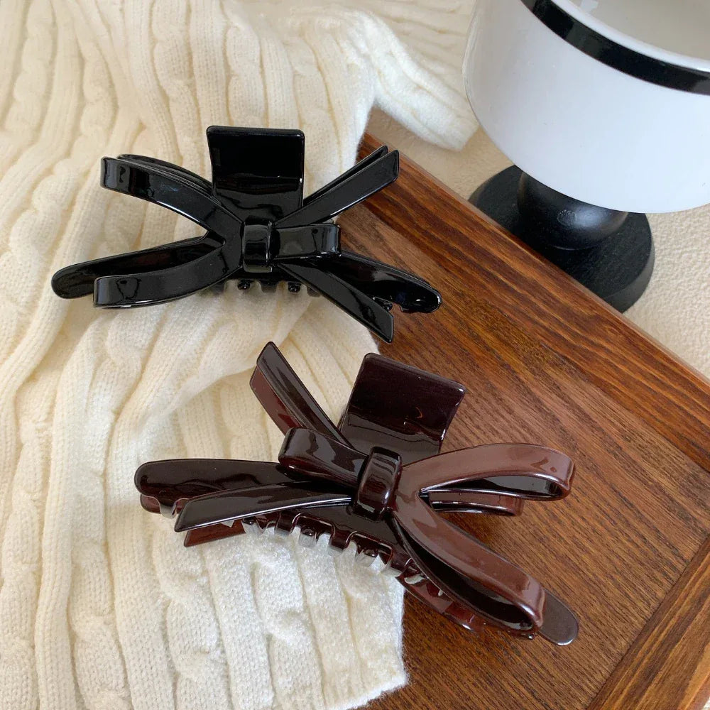 black and brown glossy bow claw clips on a wooden tray