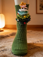 Close-up of a green ribbed knit crew sock featuring a handmade crocheted Christmas tree with colorful ornaments and a yellow star.