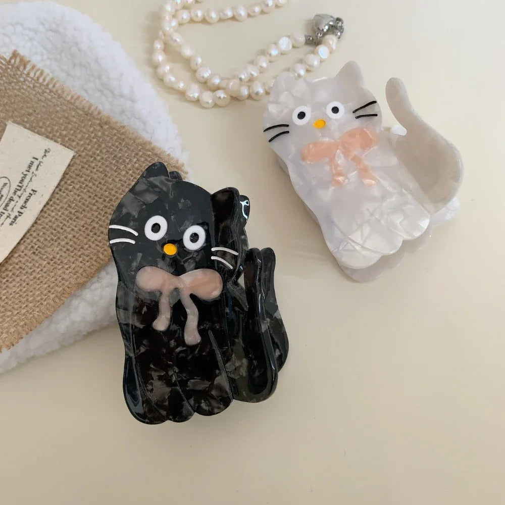White and black marbled cat hair clips with pink bows and pearl necklace
