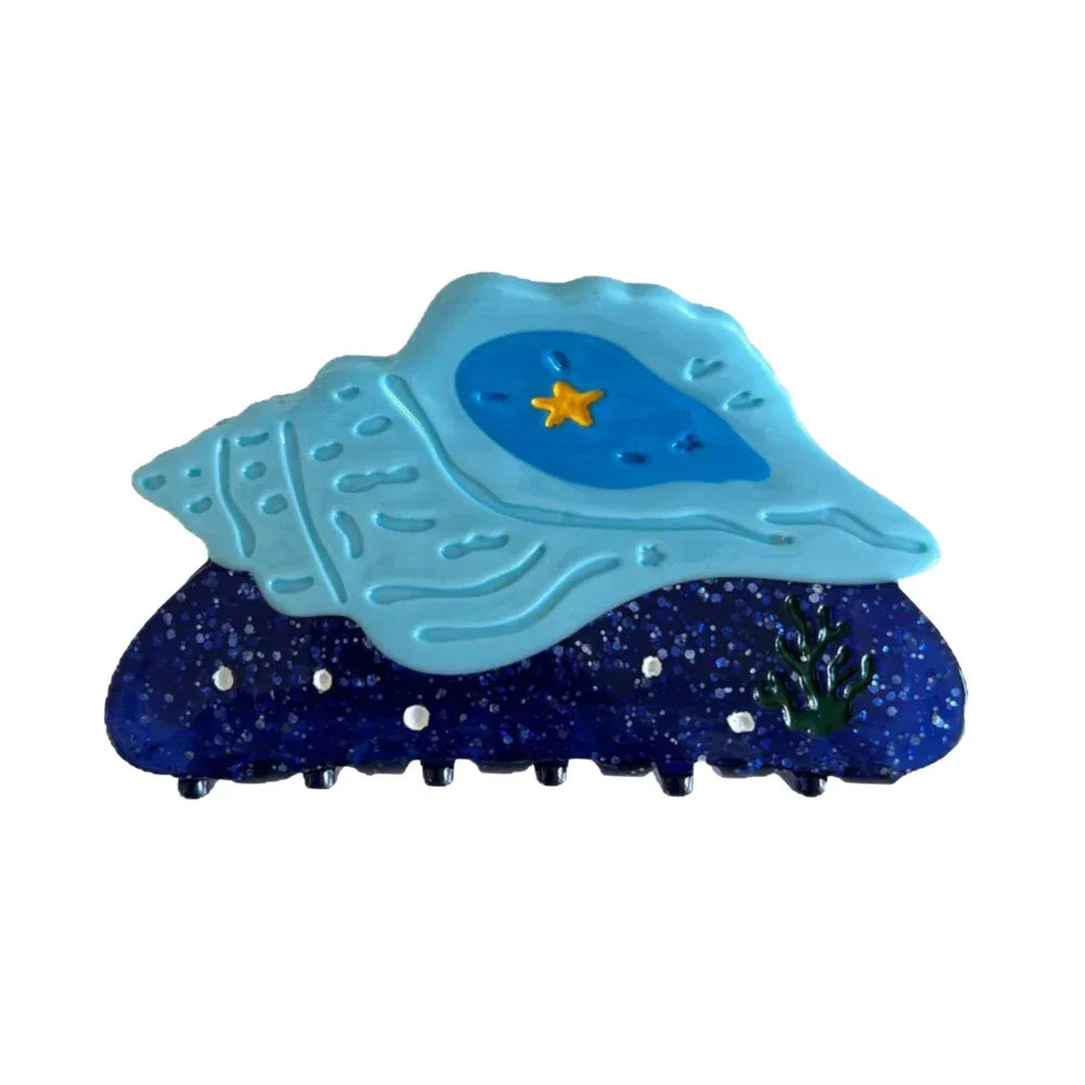 Blue seashell hair clip with a yellow star and sparkle accents