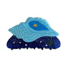 Blue seashell hair clip with a yellow star and sparkle accents