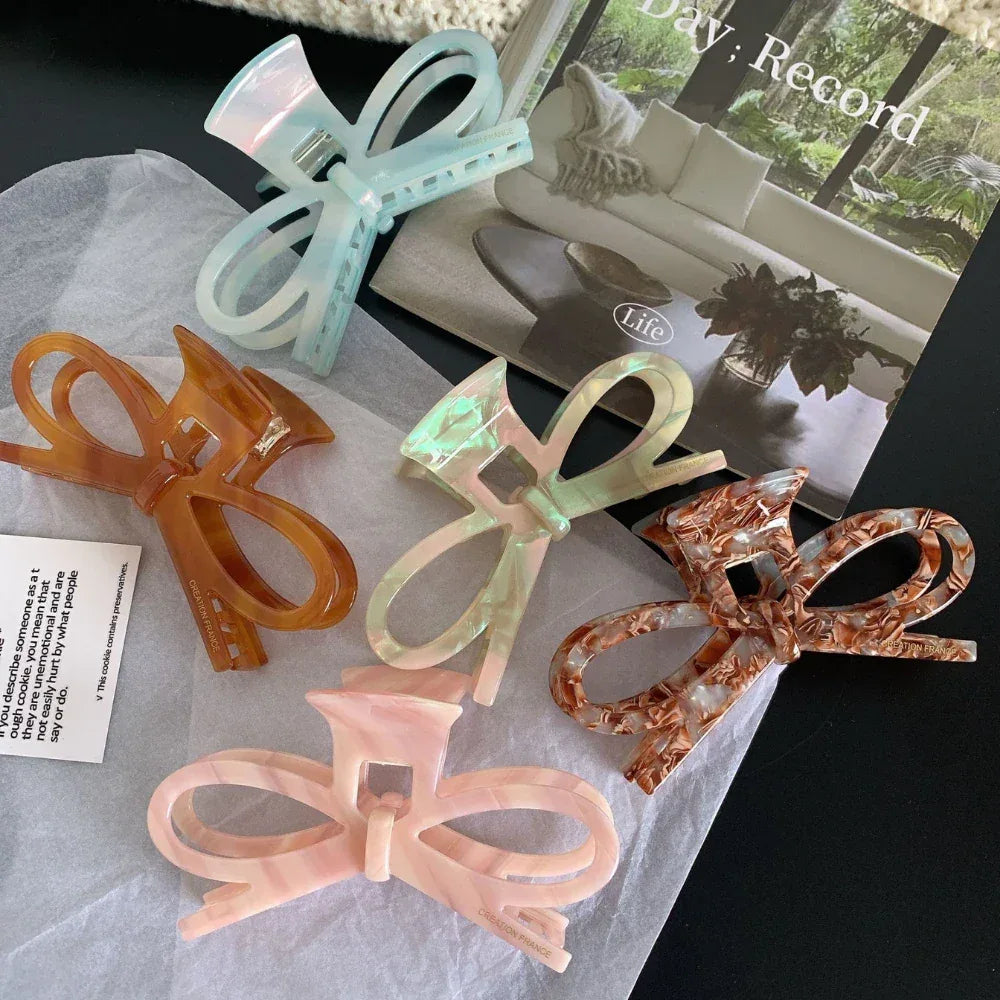 collection of bow hair claw clips in various colors including blue, amber, pink, and brown