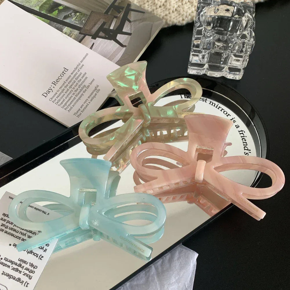 bow hair claw clips in blue, pink, and green reflected on a mirror