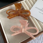 amber and pink bow hair claw clips in a wooden tray