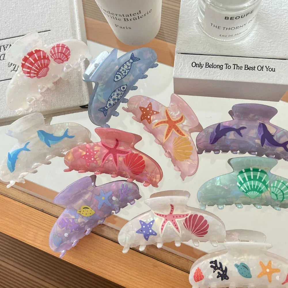 Various iridescent hair claw clips with nautical designs displayed