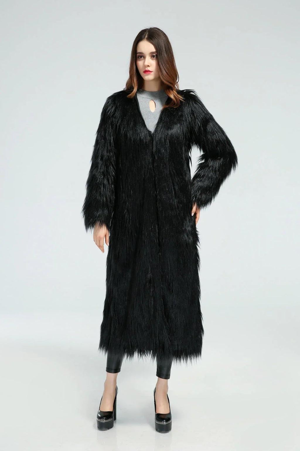 Woman posing in a long black faux fur coat with hands on hips