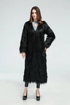 Woman posing in a long black faux fur coat with hands on hips