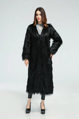 Woman posing in a long black faux fur coat with hands on hips