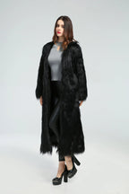 Woman standing in a long black faux fur coat, angled slightly