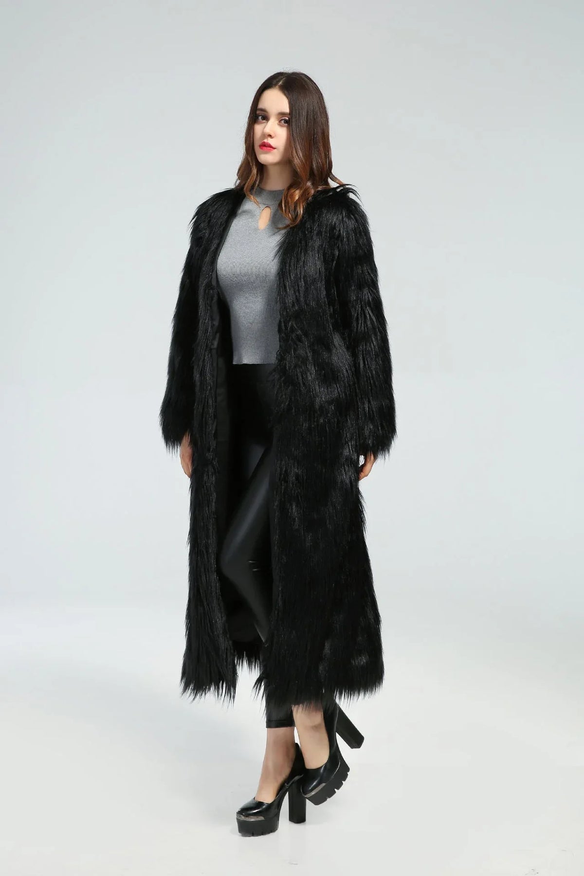 Woman standing in a long black faux fur coat, angled slightly