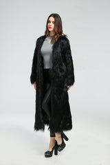 Woman standing in a long black faux fur coat, angled slightly