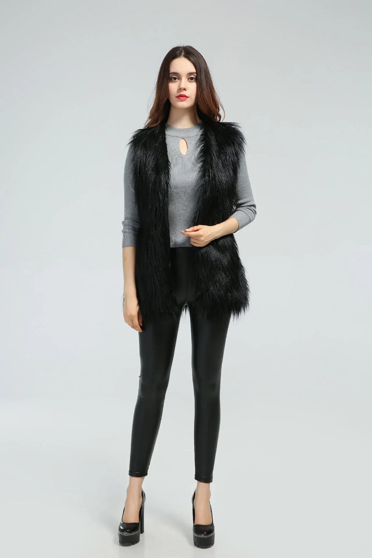 Woman wearing a black faux fur vest over a grey long-sleeved shirt and black leggings Main image