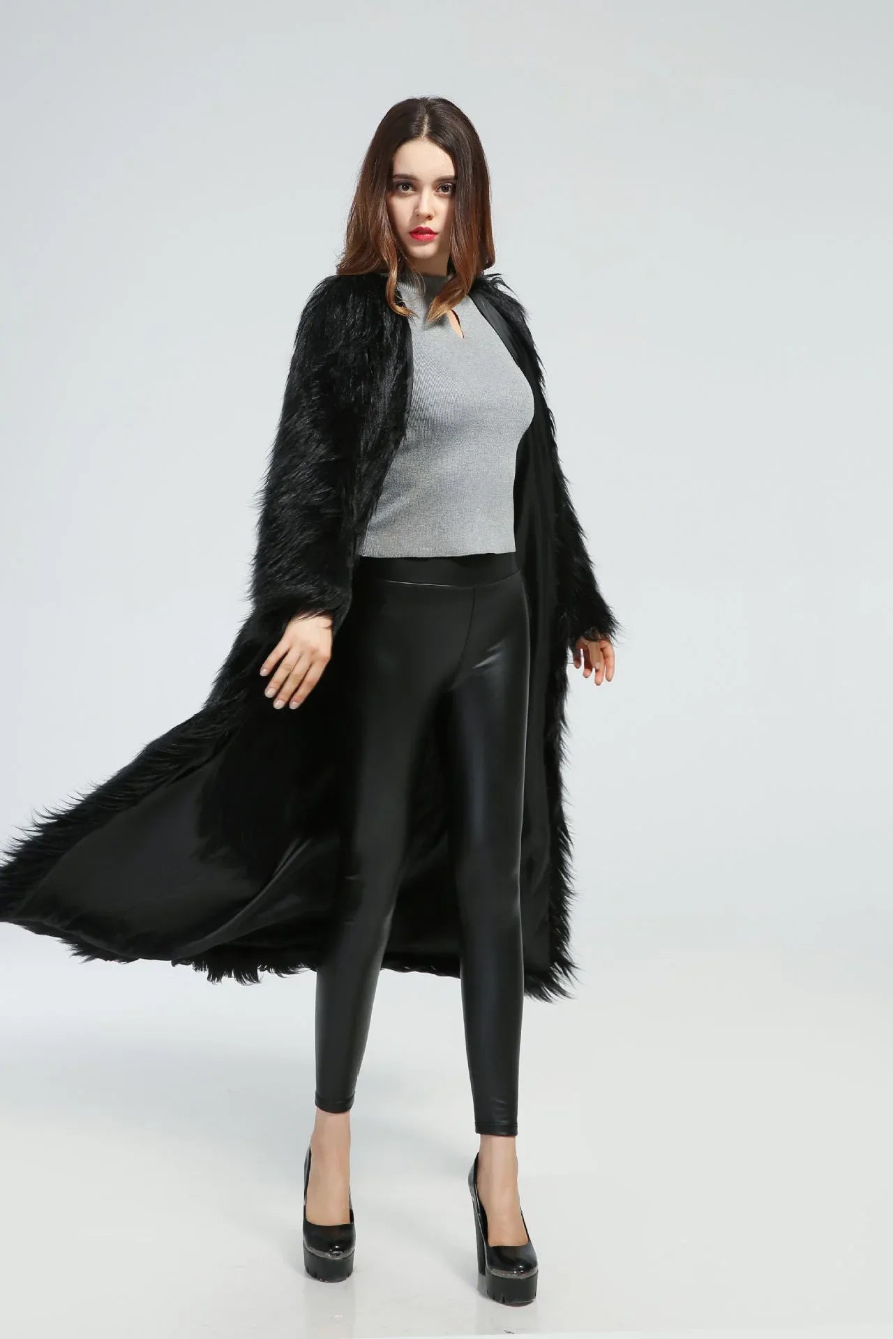 Woman wearing a long black faux fur coat with one side open, showing movement