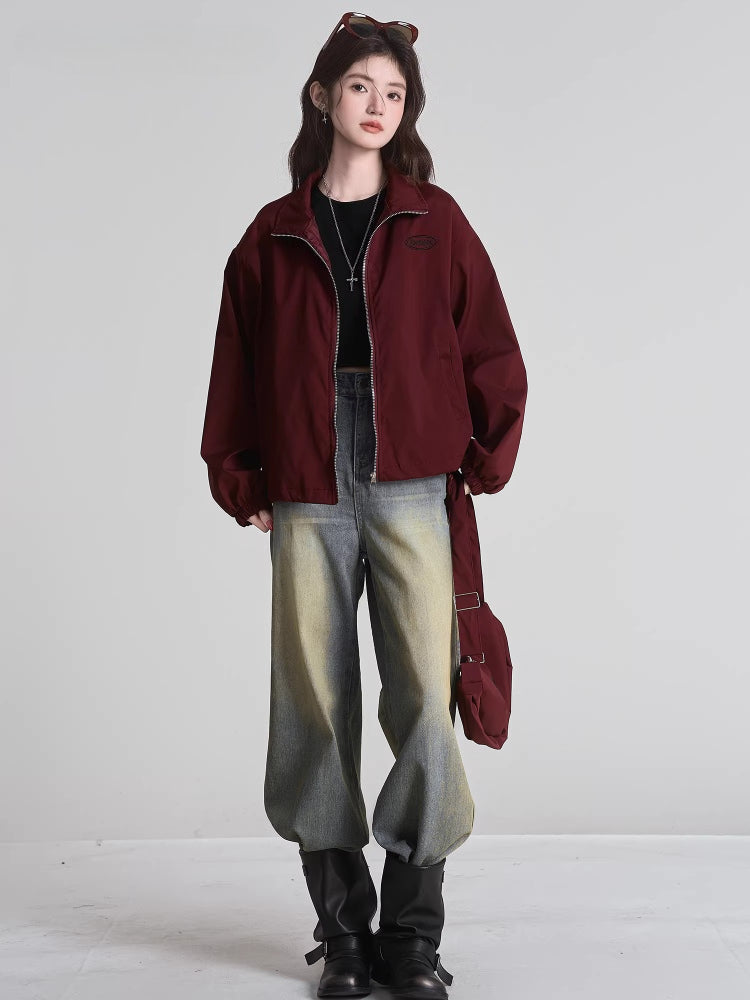 Model posing in the burgundy bomber jacket, styled with jeans and boots.