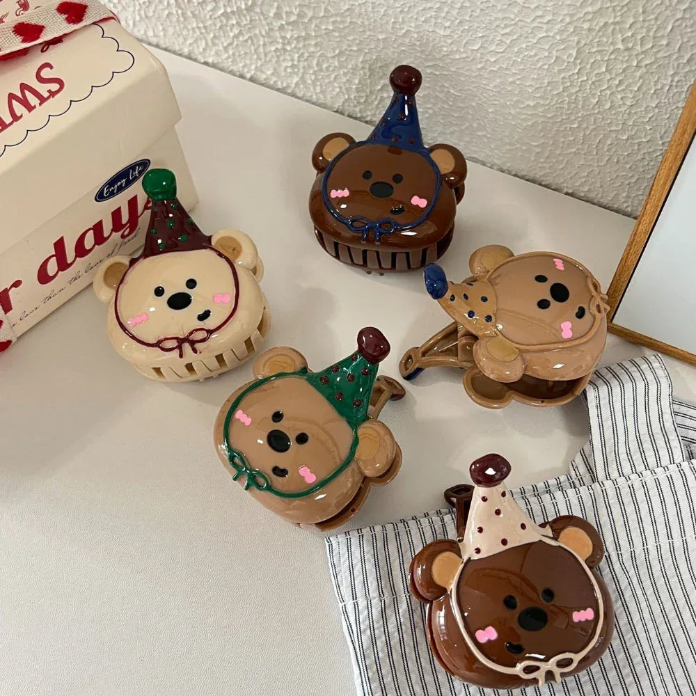 A dynamic arrangement of five bear-shaped hair clips with party hats, viewed from a slightly elevated angle, highlighting their playful design.