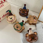 A dynamic arrangement of five bear-shaped hair clips with party hats, viewed from a slightly elevated angle, highlighting their playful design.