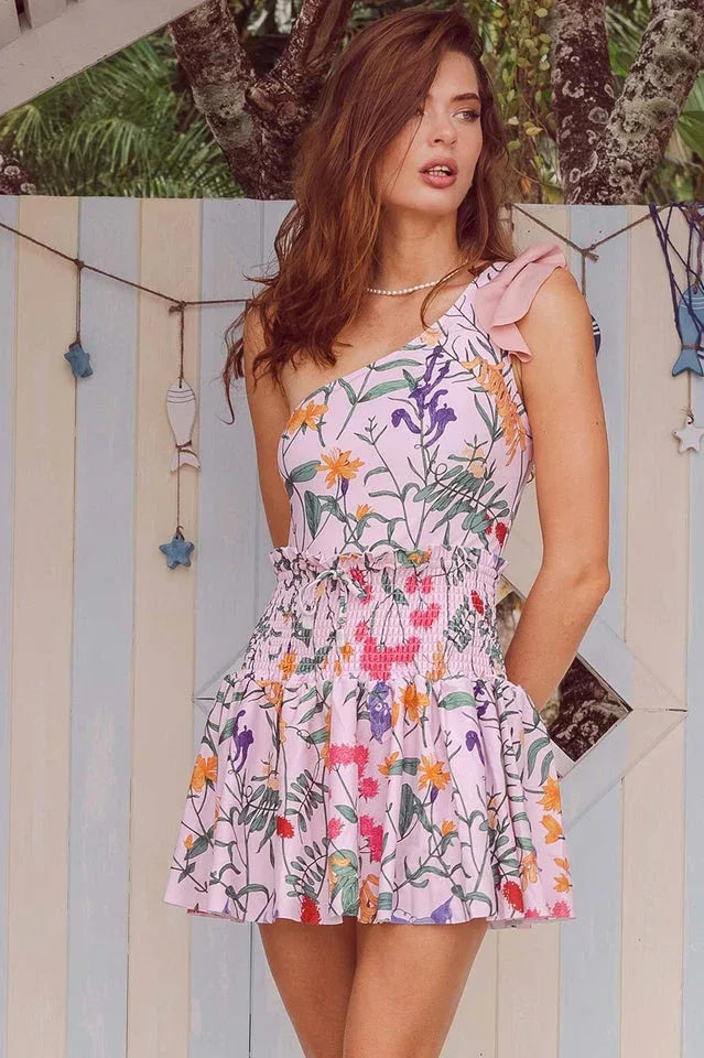Woman wearing a pink floral print smocked-waist mini dress with ruffled trim.