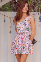Woman wearing a pink floral print smocked-waist mini dress with ruffled trim.