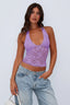 Woman wearing a purple lace halter top with blue jeans, side view