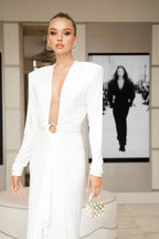 Close-up of a woman in a white gown with a plunging neckline and a ring accent at the waist.