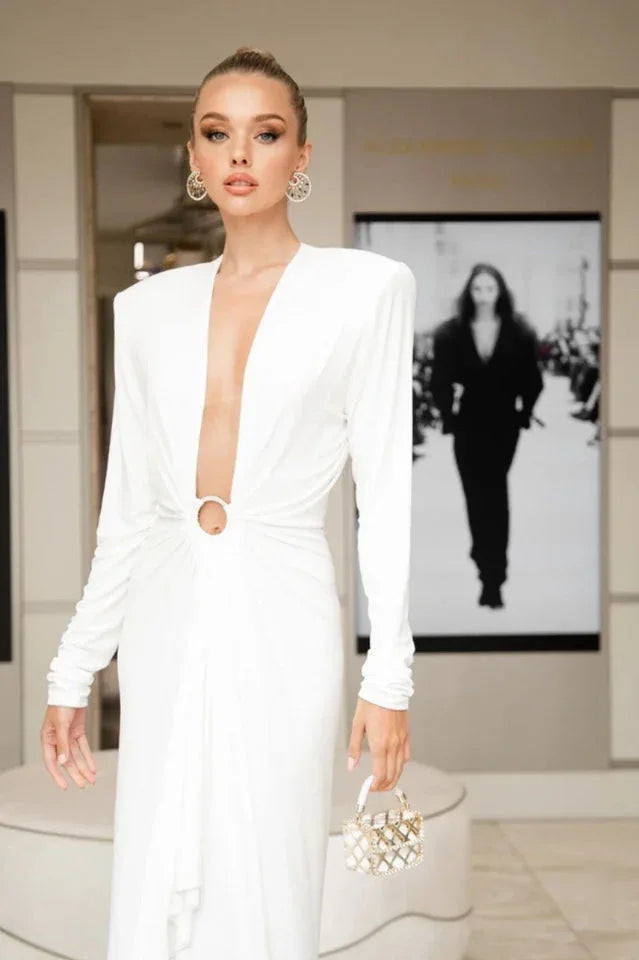 Close-up of a woman in a white gown with a plunging neckline and a ring accent at the waist.