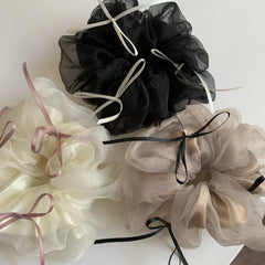 A collection of three large scrunchies in ivory, black, and taupe, each with contrasting ribbon accents.