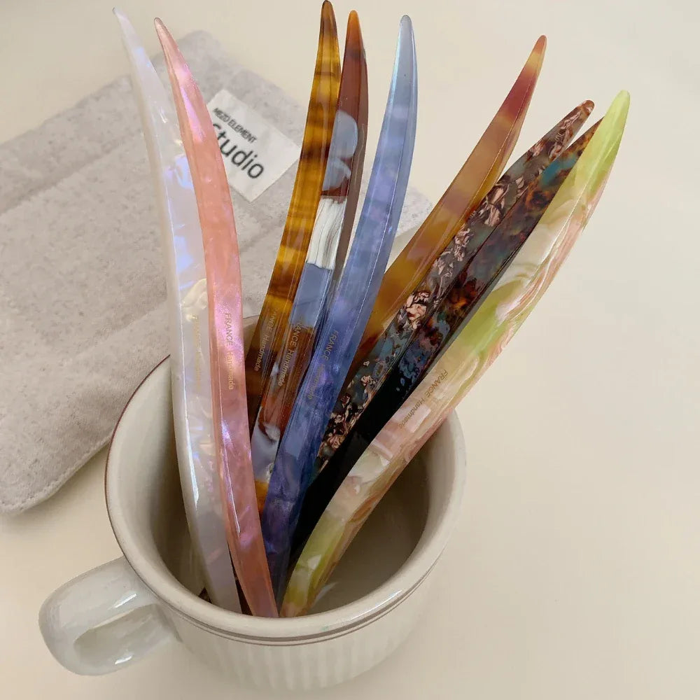 collection of curved marbled acetate hair pins in a white mug