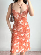 Woman holding a brown crocodile-embossed handbag while wearing a floral print midi slip dress.