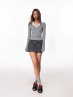 Full body shot of a model wearing a grey long-sleeved top with a white contrast collar, leopard print skirt, socks, and sneakers.