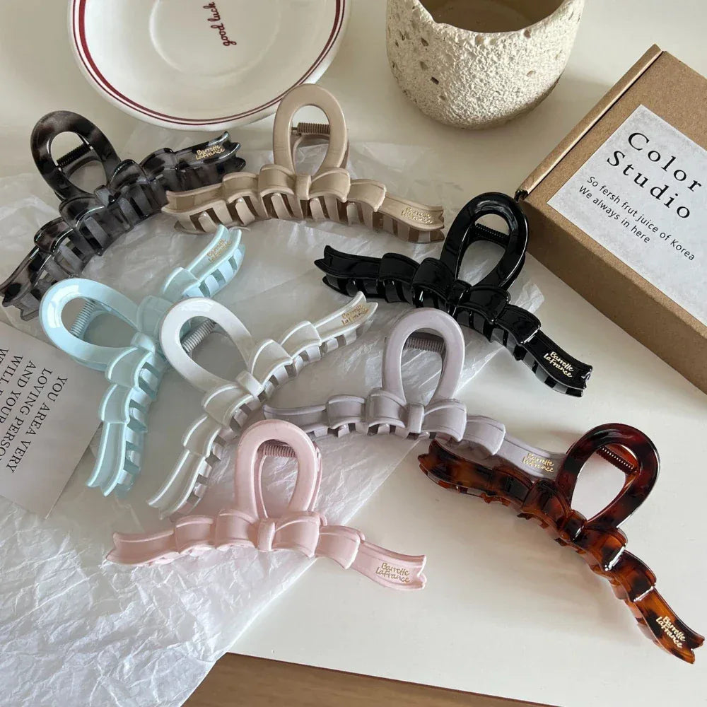 A top-down view of a variety of bow claw clips laid out on a white surface.