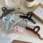 A top-down view of a variety of bow claw clips laid out on a white surface.
