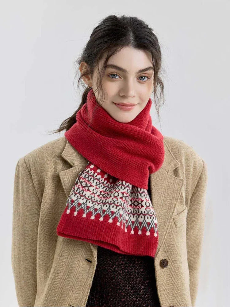 Close-up of a woman wearing a red knit scarf with a Fair Isle pattern on the ends.