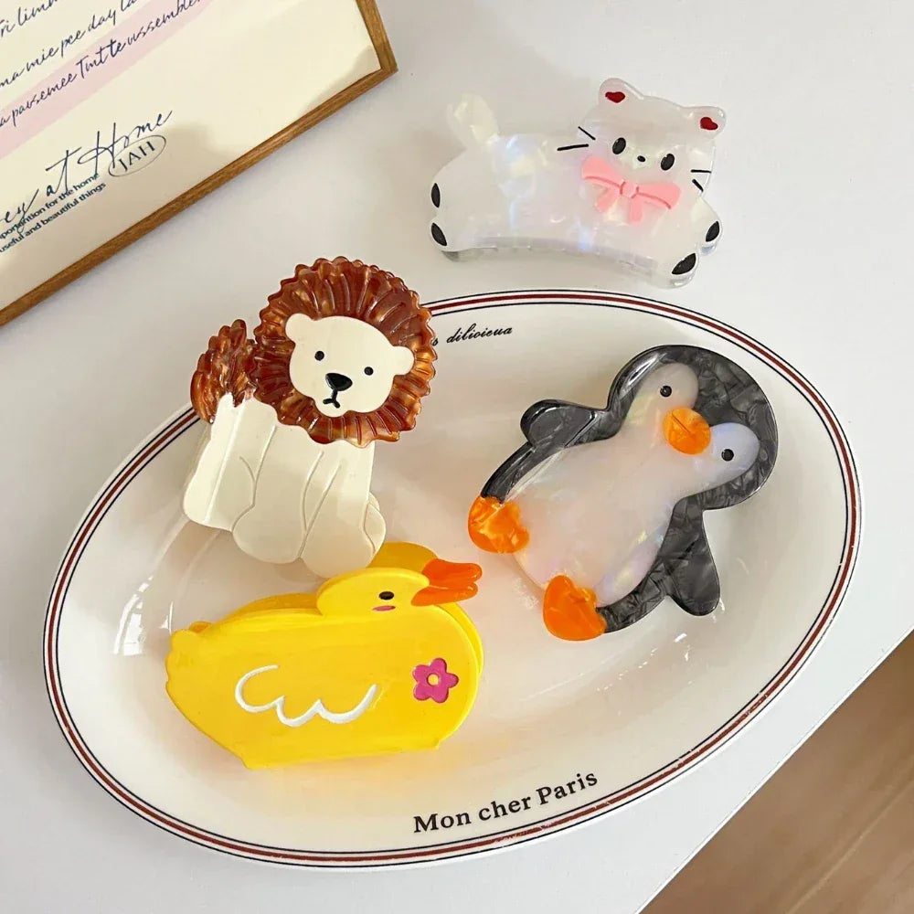 collection of animal hair claw clips including a cat, lion, penguin, and duck on a white oval plate