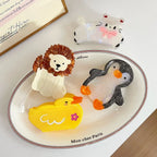 collection of animal hair claw clips including a cat, lion, penguin, and duck on a white oval plate